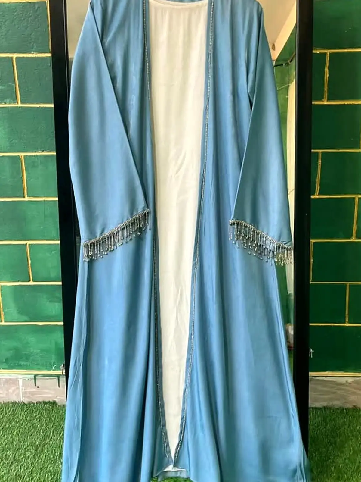 Sky blue open abaya with an ivory inner and beaded fringe cuffs, on a hanger